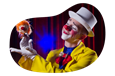 A clown in a yellow suit performs with a puppet.