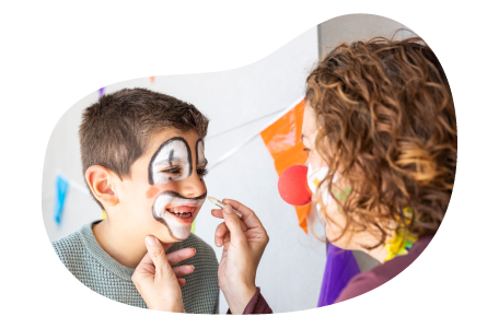 A face painter draws a clown face on a child.