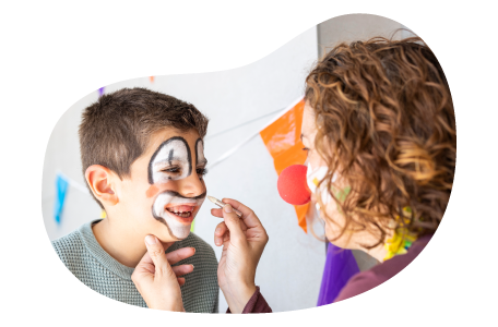 A face painter draws a clown face on a child. A face painter draws a clown face on a child.