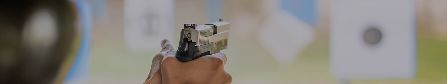 A customer at a shooting range points their gun at a target. A customer at a shooting range points their gun at a target.