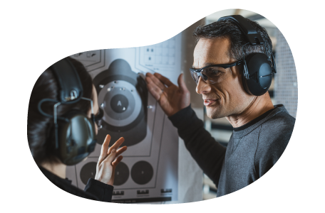 An employee helps a customer at a gun range calculate their score.