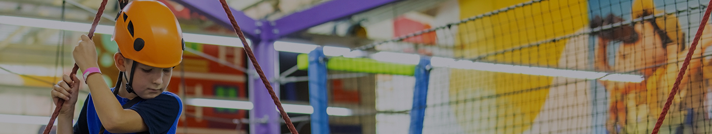 A child wearing climbing gear at an indoor playground.