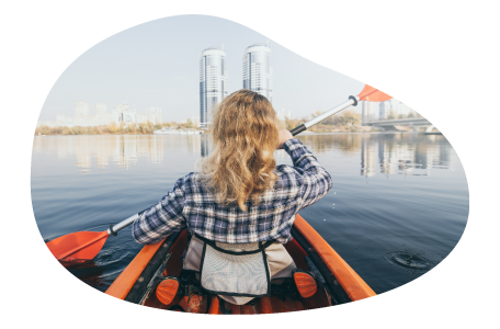 A member of a marina paddles a kayak on a river.