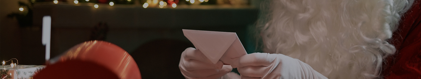 A costumed Santa holds a piece of mail from a child.