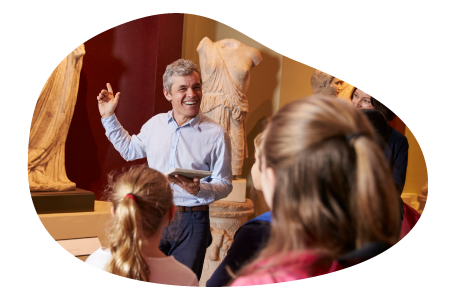 A tour guide shows a group a statue display at a museum. A tour guide shows a group a statue display at a museum.