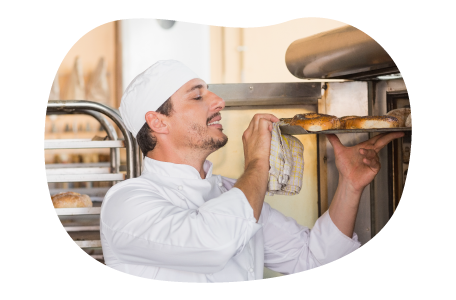 A baker takes bagels out of an oven.