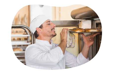 A baker takes bagels out of an oven. A baker takes bagels out of an oven.