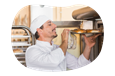 A baker takes bagels out of an oven.