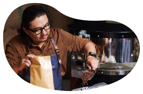 An employee scoops freshly roasted coffee beans into a bag. An employee scoops freshly roasted coffee beans into a bag.