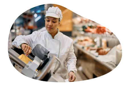 Deli employee slicing meat.
