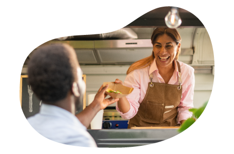 A food trailer business owner hands a customer their order