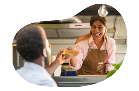 A food trailer business owner hands a customer their order A food trailer business owner hands a customer their order