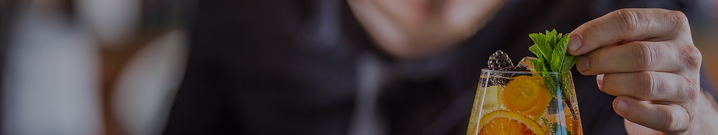 A drink with blackberries, orange, and mint crafted by a mobile bartender.