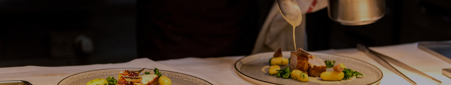 A personal chef adds a touch of sauce to a gourmet dish.