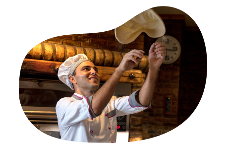 A chef tosses pizza dough in the air.