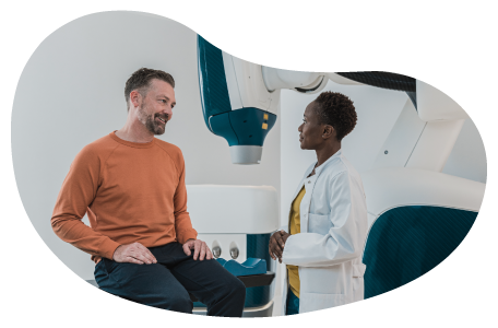 A patient speaks with a doctor in a hospital room.