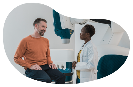 A patient speaks with a doctor in a hospital room.