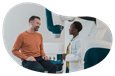 A patient speaks with a doctor in a hospital room.