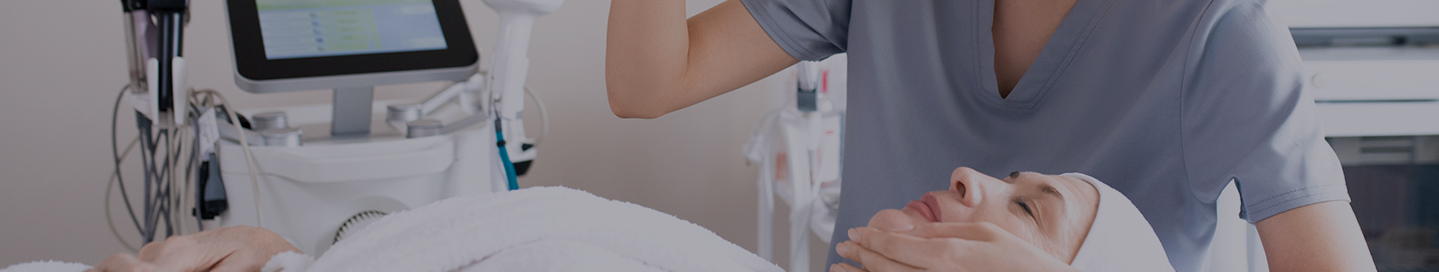 An aesthetic nurse examines a patient's face.