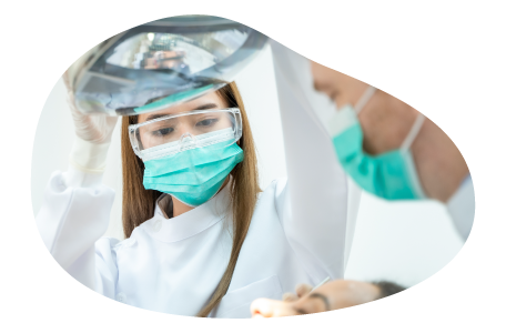 A dental assistant helps a dentist work on a patient.