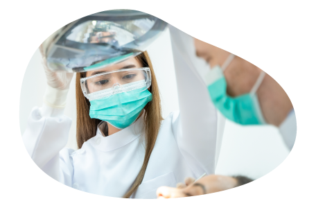 A dental assistant helps a dentist work on a patient. A dental assistant helps a dentist work on a patient.