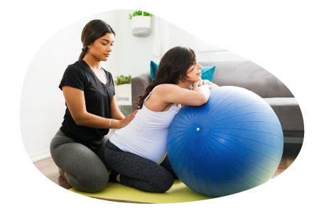 A doula works with a client using an exercise ball. A doula works with a client using an exercise ball.