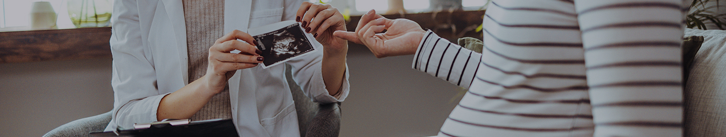 A midwife shares an ultrasound picture with a patient.