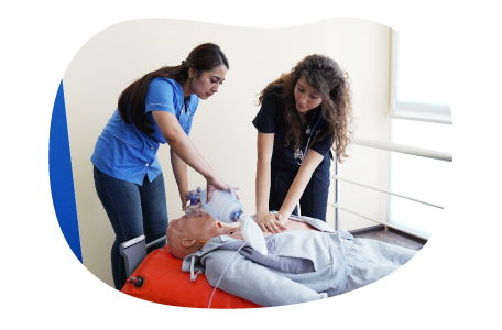 A nurse educator trains a student using a CPR manikin. A nurse educator trains a student using a CPR manikin.