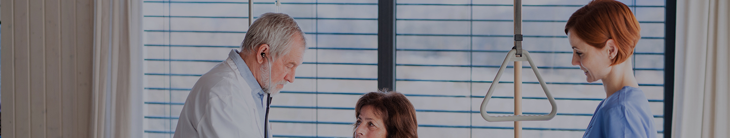 A nursing assistant helps a doctor record a patient's vitals.