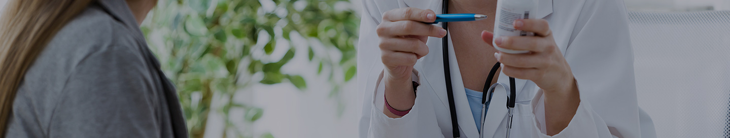 A nutritionist holding a bottle of pills explains a dietary supplement to a patient.