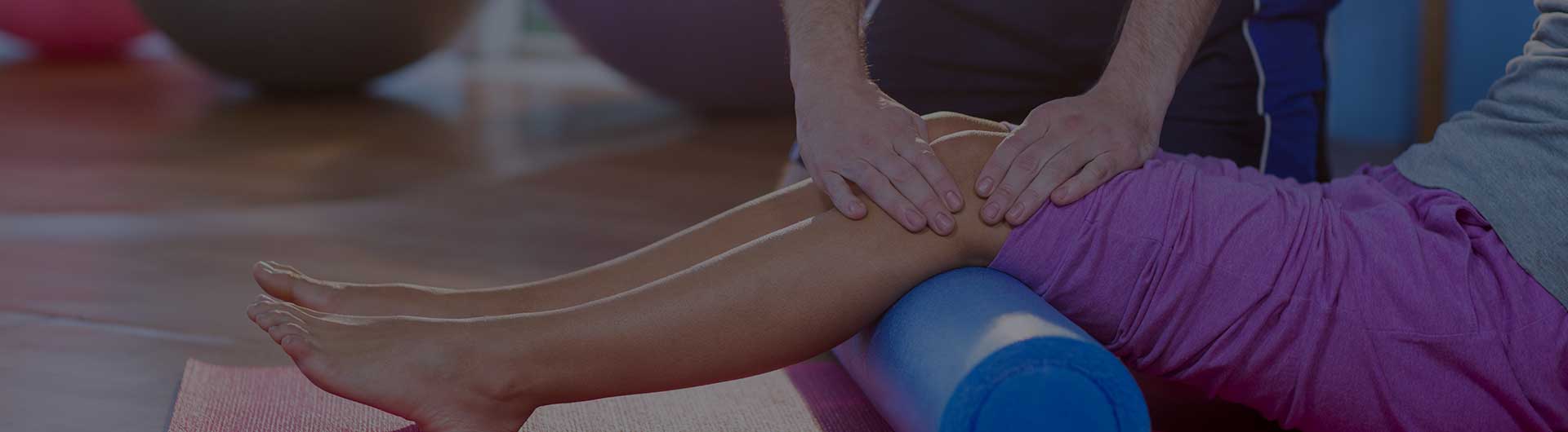 Physiotherapist assisting woman while exercising on exercise mat in clinic.