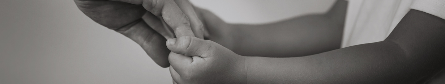 Child holding hands with an adult