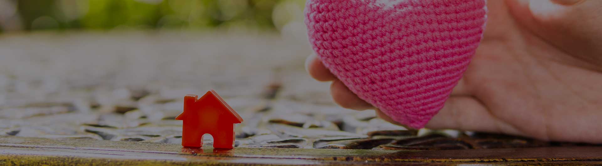 Hand are hold pink heart and home model.