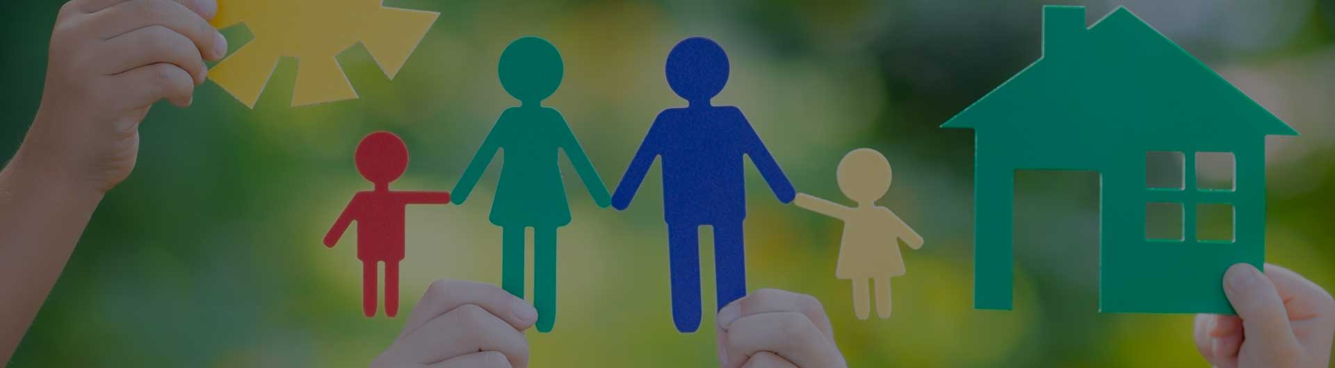 Paper house and family in hands against spring green background.