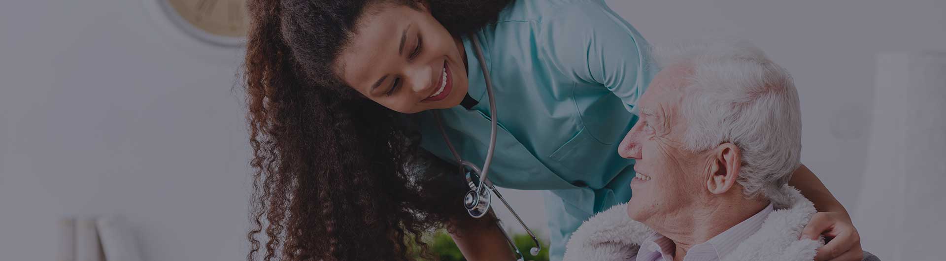 Nurse with a stethoscope covering an elderly man with a blanket in a nursing home.