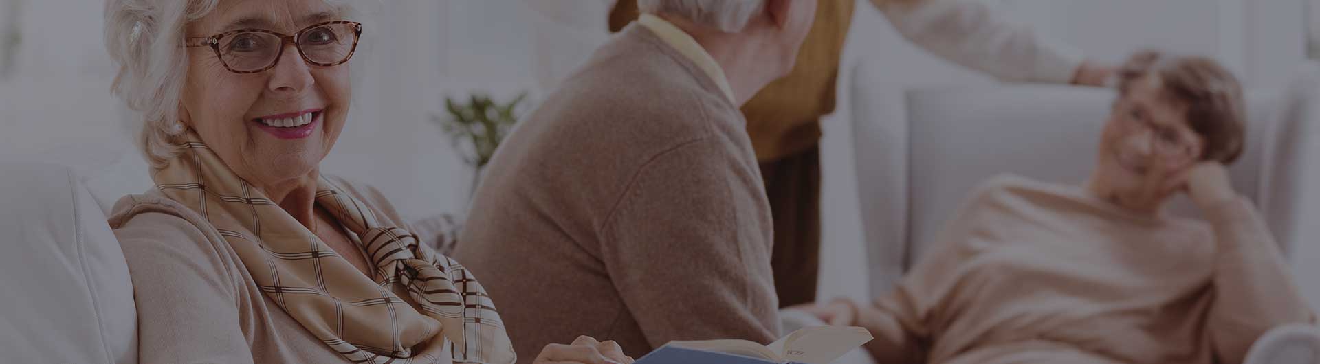 Elderly woman reading a book and her friends chatting with each other.
