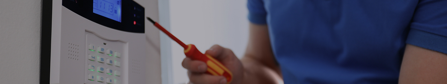 A contractor installs a new alarm system keypad in a client's home.