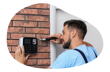 A contractor installs an alarm keypad at the front door of a home.