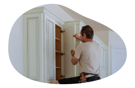 A contractor installing a kitchen cabinet.