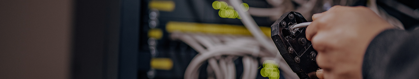 An installation contractor uses a wire stripper on a length of cable.