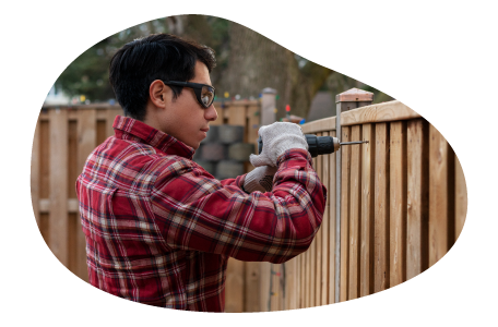 Contractor installing a fence in a yard.
