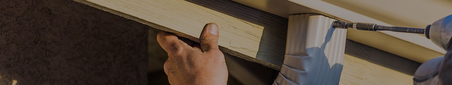 A contractor installs a new gutter on a home.