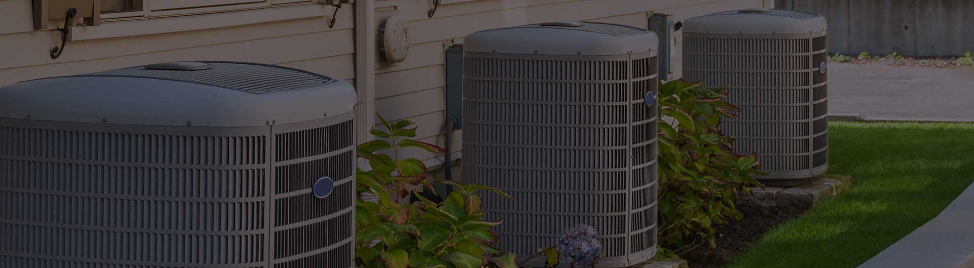 Three HVAC units sitting behind an apartment complex. Three HVAC units sitting behind an apartment complex.