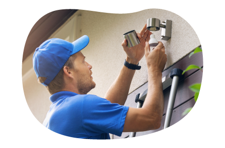 A contractor installs an exterior light over a garage.