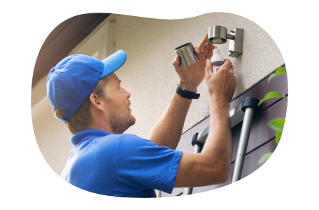 A contractor installs an exterior light over a garage. A contractor installs an exterior light over a garage.