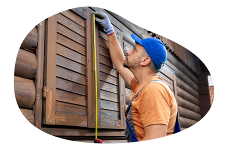 A contractor measuring the shutters on a log cabin.