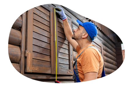 A contractor measuring the shutters on a log cabin. A contractor measuring the shutters on a log cabin.