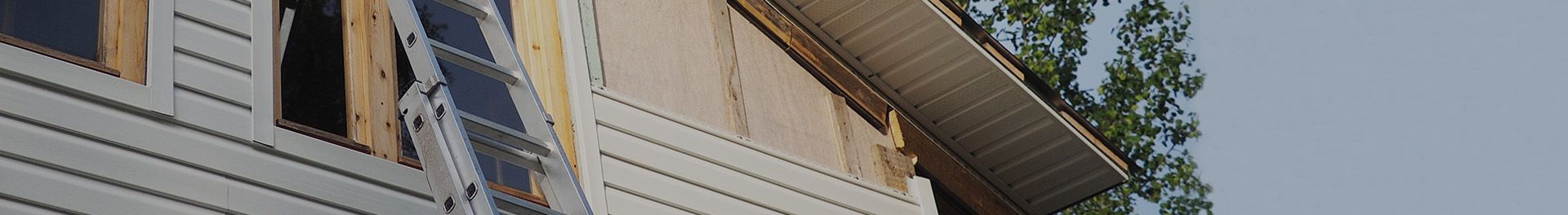 Ladder leaning against the side of a house being re-sided.