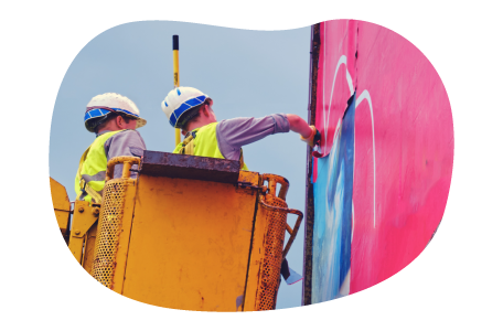 Sign installers in a boom lift painting a billboard.