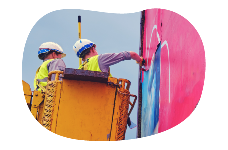 Sign installers in a boom lift painting a billboard. Sign installers in a boom lift painting a billboard.